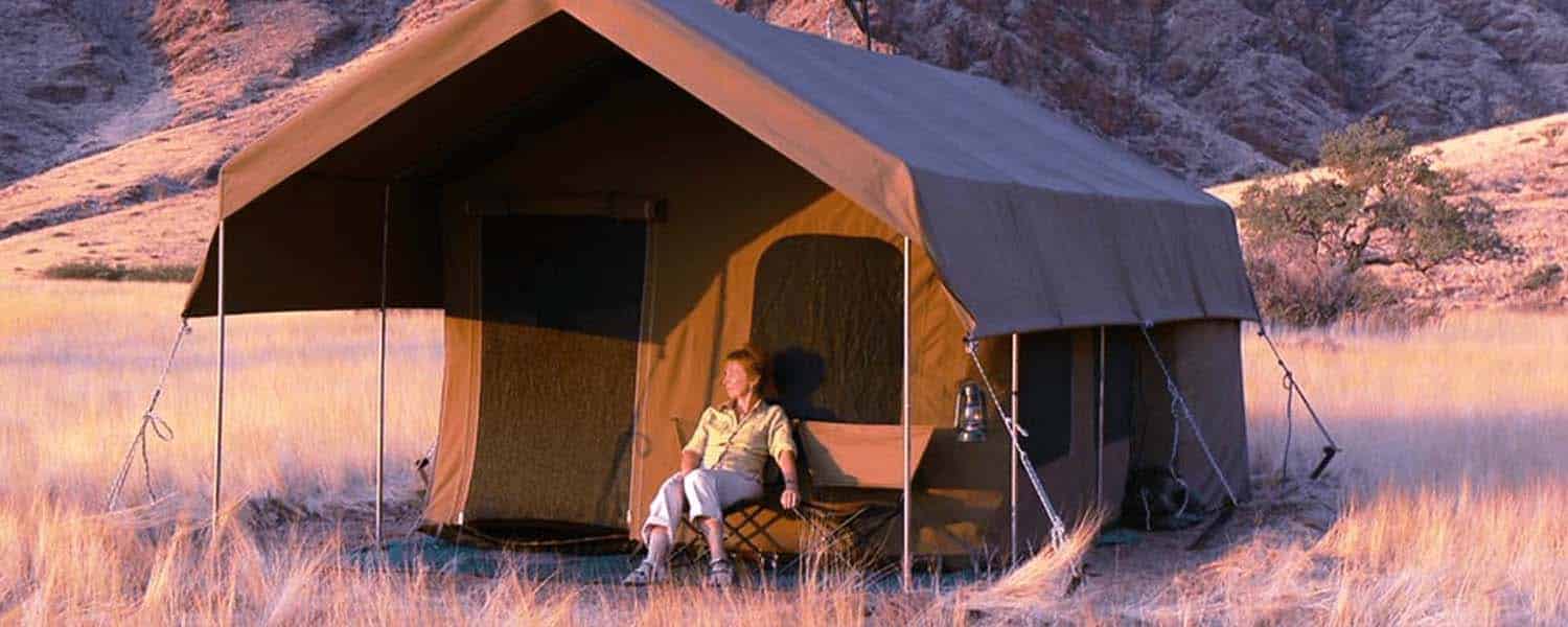 banner camping safari donna seduta nella veranda della sua tenda in luxury camping safari