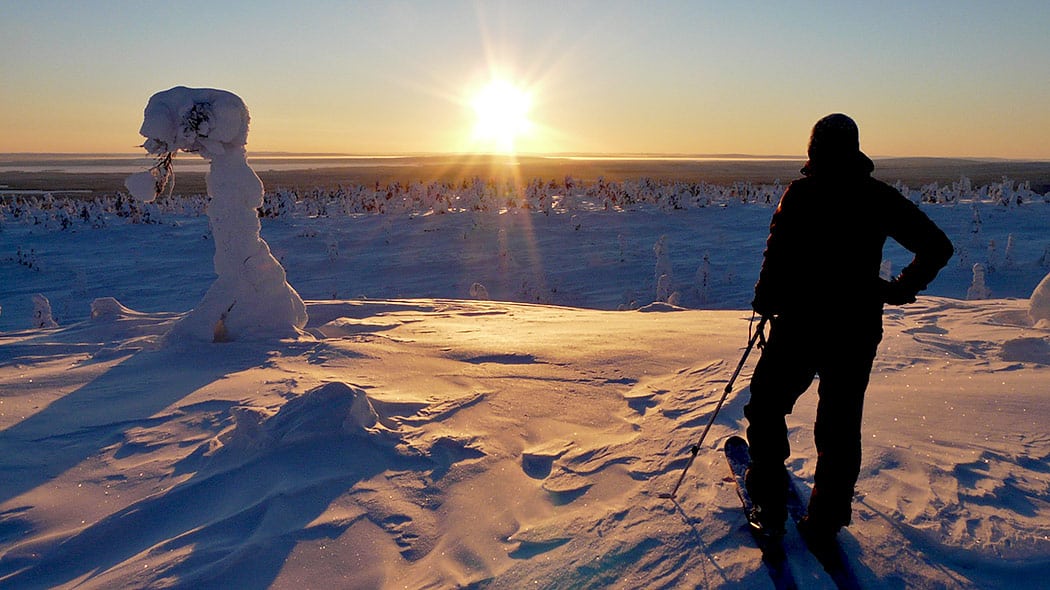 Riisitunturi_lumikenkailija_maiseman_aarella_1050px_HanneleKyto uomo con le racchette da neve ammira il paesaggio del Riisitunturi National Park
