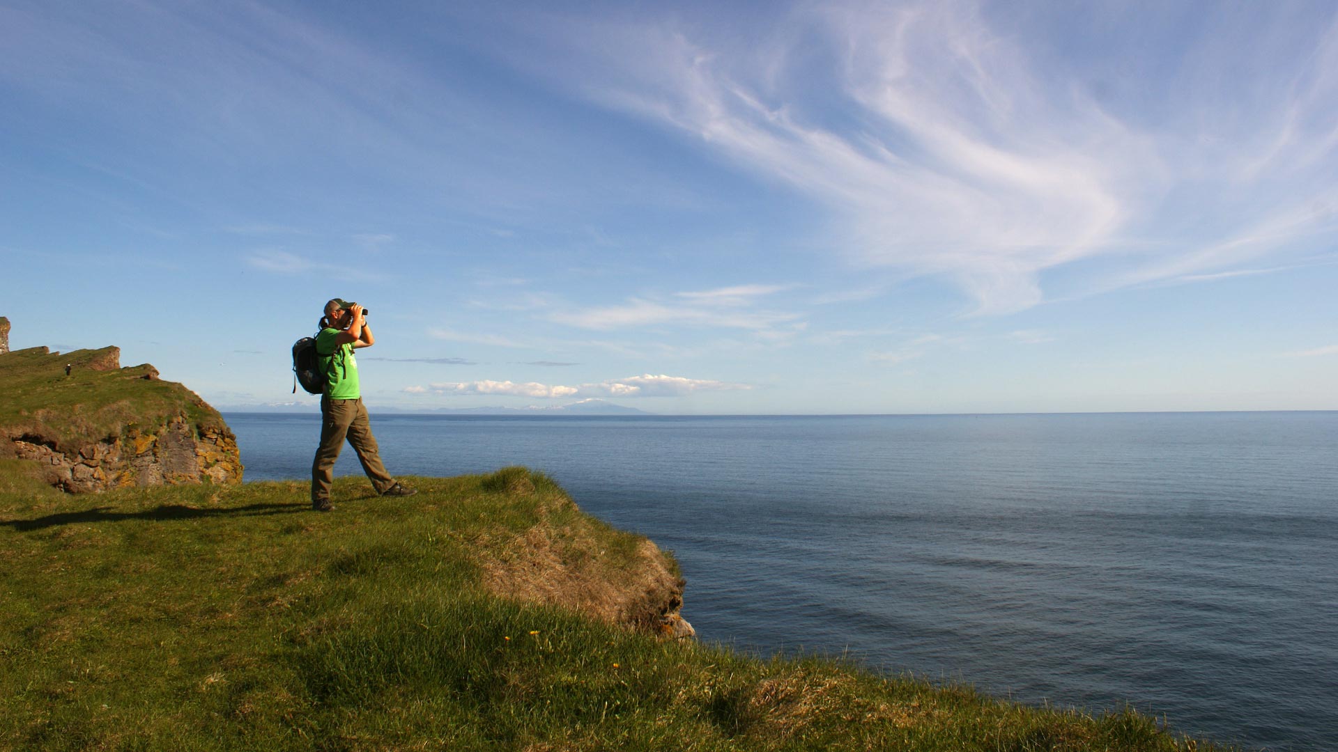 latrabjarg-westfjords-iceland turista scruta l'orizzonte da una scogliera di Latrabjarg