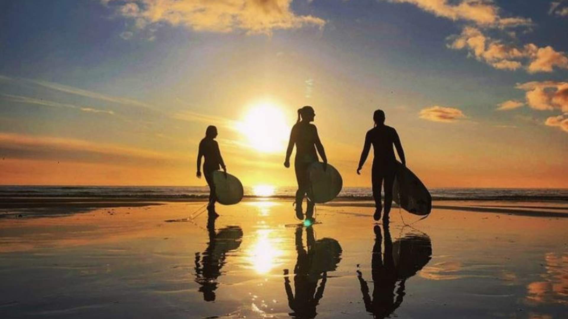 midnight sun lofoten islands ragazzi su una spiaggia delle Lofoten con la tavola da surf sotto il sole di mezzanotte